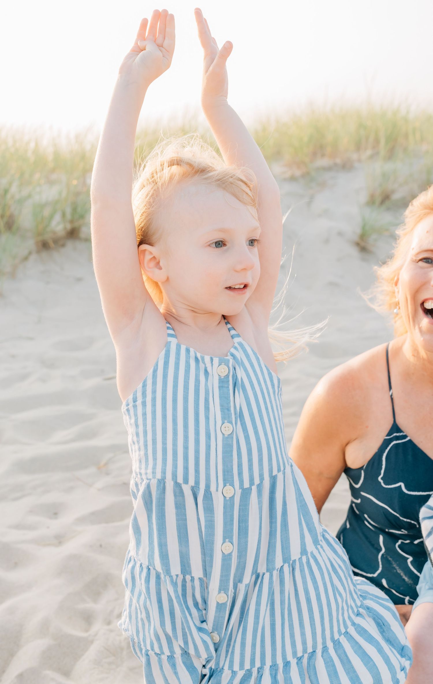 Young girl in a blue stripped dress dances on the sea girt beach at the jersey shore.