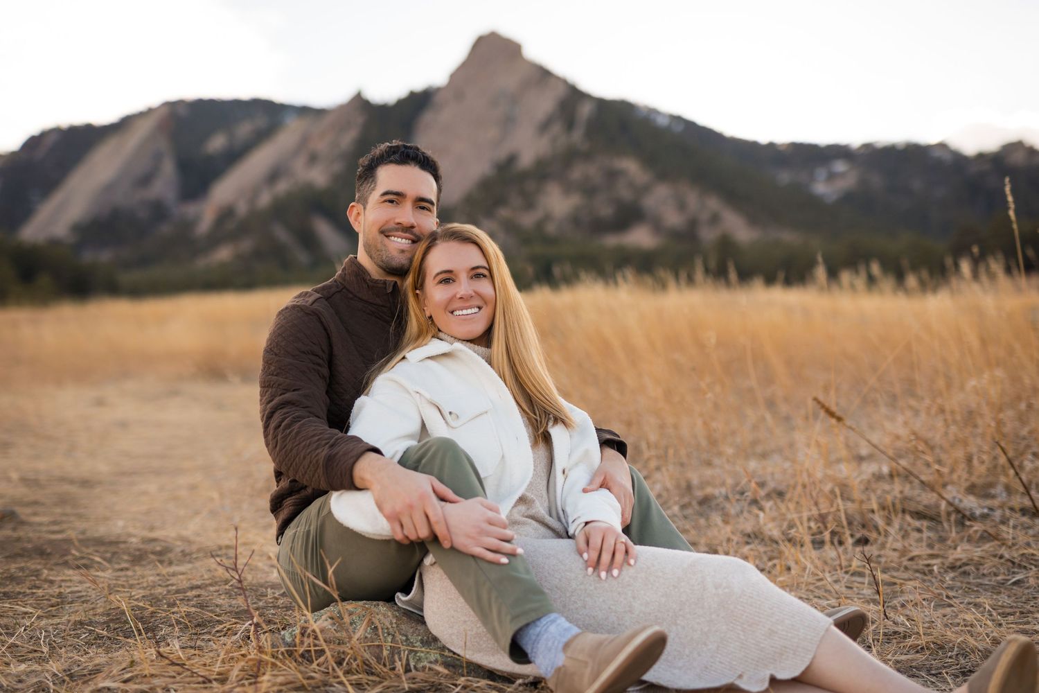 A couple sharing a joyful moment together in front of a columned building during golden hour.