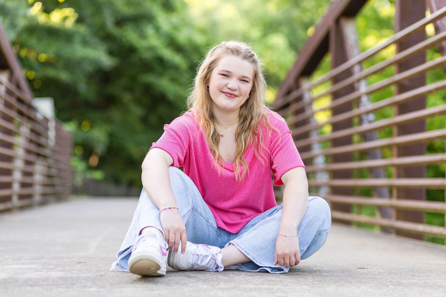 High school senior sitting on bridge.
