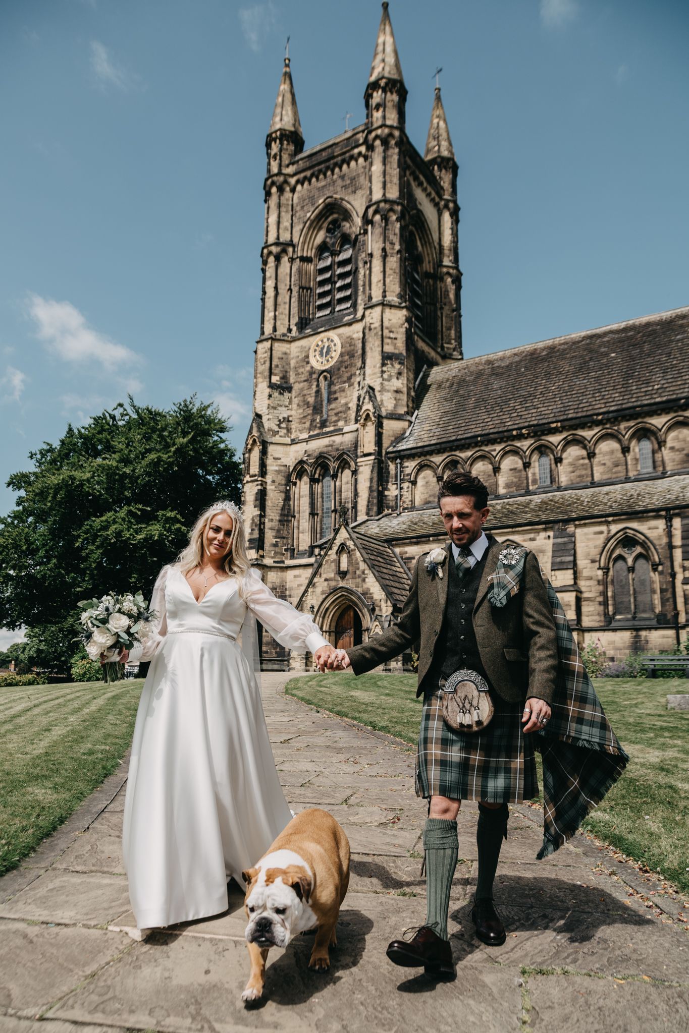 Beautiful wedding ceremony outside gothic church architecture with pet dog present.