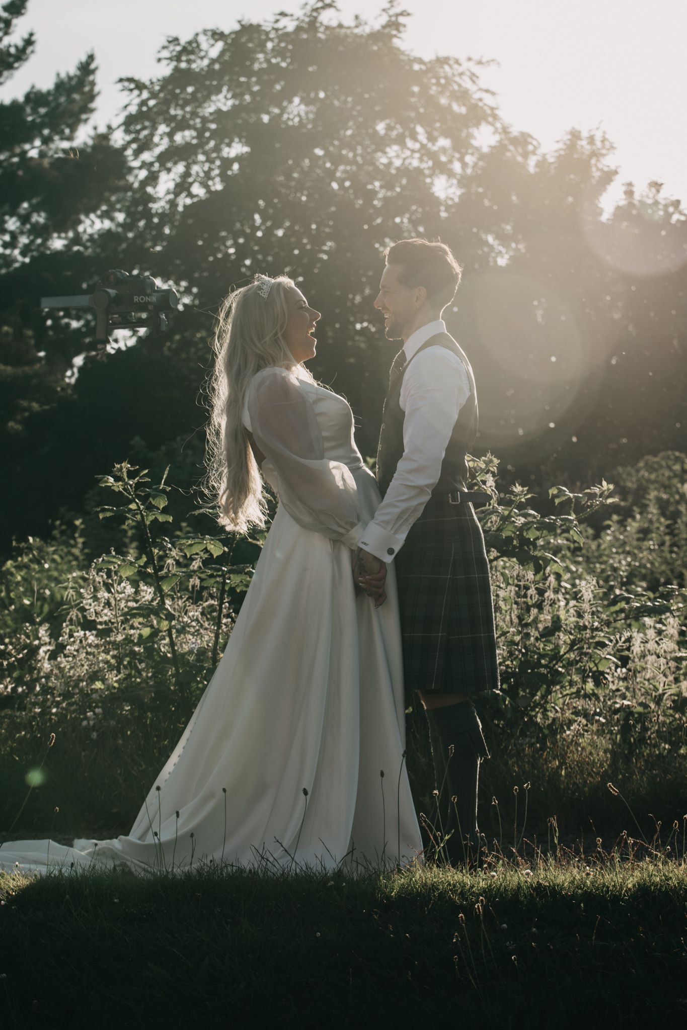 Romantic sunset portrait of couple in wedding attire among trees.