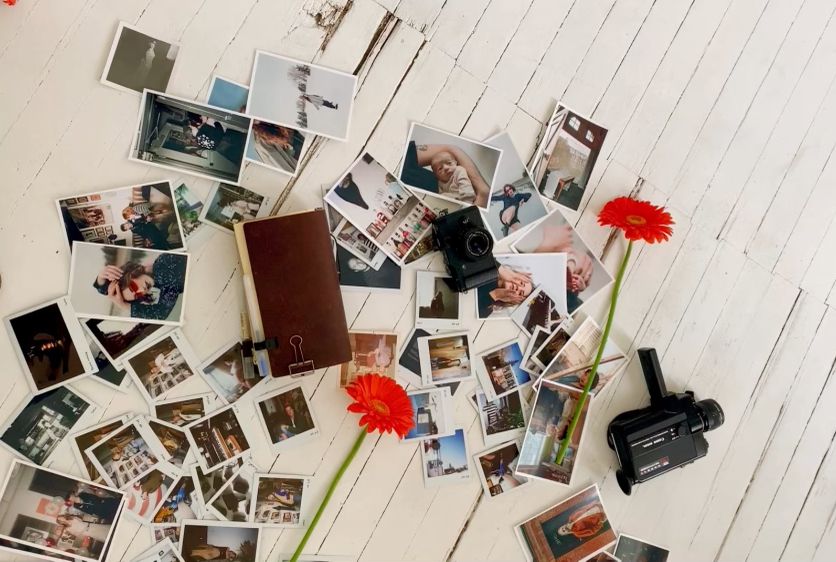 Collection of vintage Polaroid photos scattered on a white wooden surface with red flower decorations.