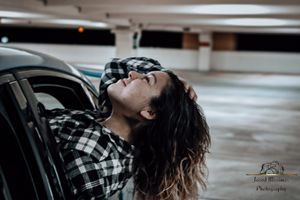 Moody black and white photo of someone reclining in a parking garage.