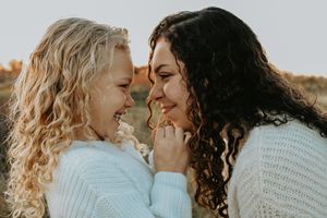 Intimate portrait of couple in light sweaters sharing tender moment outdoors.