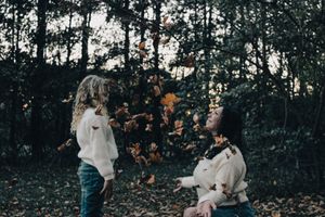 Two people in light clothing embracing outdoors during autumn season.