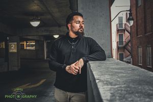 Person in black shirt checking time while standing in a dimly lit urban setting.