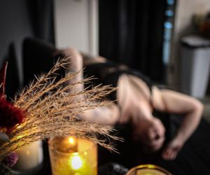 Moody still life with candles glowing and dried pampas grass creating atmospheric shadows.