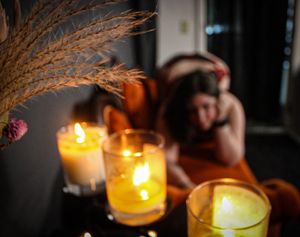Atmospheric scene with glowing candles and dried pampas grass creating moody ambiance.