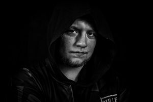 Dramatic black and white portrait of a person wearing a dark hooded sweatshirt.