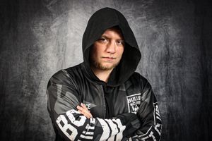Athletic figure in a black hooded jacket with white text design against a grey background.