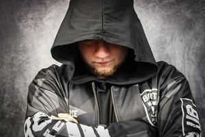 Close-up shot of a person in a black hoodie with hidden face against light background.