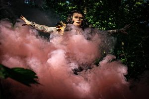 Colorful smoke bombs create dramatic effect in wooded outdoor photo session.
