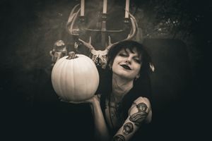 Dark moody scene with white pumpkin and antler decorations in vintage styling.