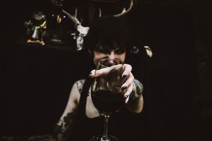 Dark atmospheric photo of someone pouring a drink near antler decorations.