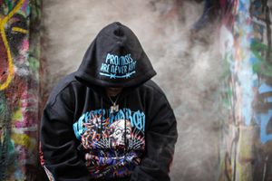 Urban streetwear hoodie displayed in sequence against colorful graffiti wall with dramatic lighting.