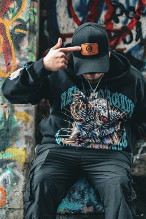 Urban fashion photography of hoodie and cap against colorful graffiti wall.