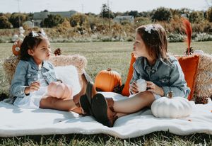 Two people laying in a grassy field with white pumpkins during an autumn photoshoot.
