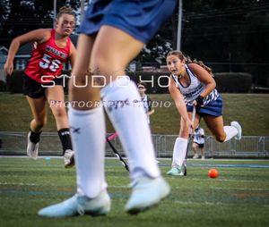 Soccer player wearing blue uniform kicking ball on outdoor sports field during competitive match.