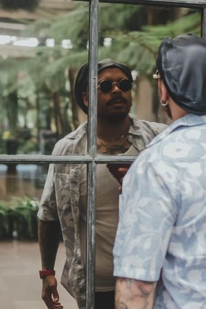 Person in casual wear reflected in window pane outdoors.