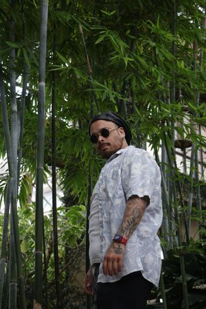 Figure in white camo jacket standing among tall bamboo trees in a garden.