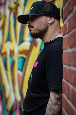 Person in black outfit poses against colorful graffiti wall with urban street art.