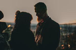 Silhouetted couple having an intimate moment against city lights at dusk.