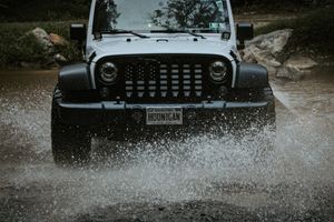Jeep Wrangler splashing through water on an off-road adventure.
