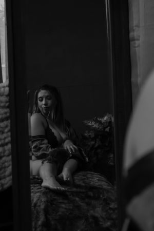 Figure reclining in dimly lit interior space with dramatic shadows.