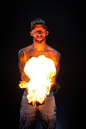Dramatic fire performance with flames emerging against black background.