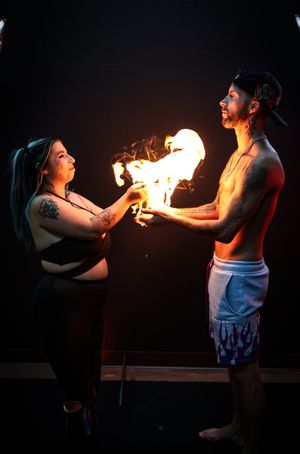 Two performers demonstrate fire breathing techniques in a dramatic dark photo sequence.