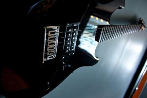 Black electric guitar with chrome hardware photographed in moody lighting.