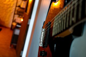 Electric guitar neck and bridge photographed in warm ambient lighting.