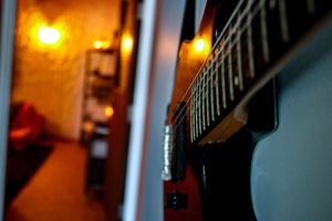Guitar fretboard detail with warm glowing lights in background.