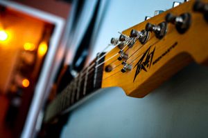 Yellow Peavey guitar headstock with tuning pegs in shallow focus.