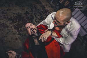 Two wrestlers engaged in an intense dramatic match move on the ground.