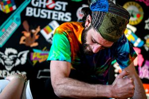 Person in tie-dye shirt against colorful Ghostbusters themed background.
