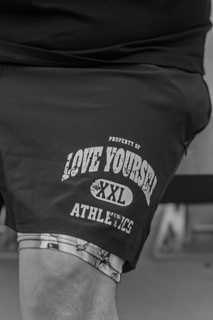 Close-up of black athletic wear with 'Love Yourself' text branding.