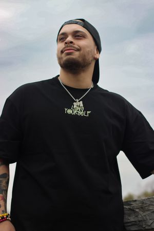 Person in black t-shirt outdoors striking poses against cloudy sky background.