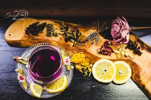 Dark moody tea service with citrus fruits, herbs and spices arranged on rustic wooden surface.