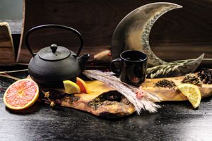 Elegant tea service display with fresh citrus slices and herbs on dark wood background.
