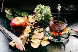 Herbal tea composition with fresh flowers, fruits and vintage teacups on black surface.