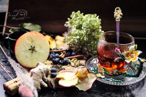 Natural tea setting with apples, herbs and vintage teaware styled on dark background.