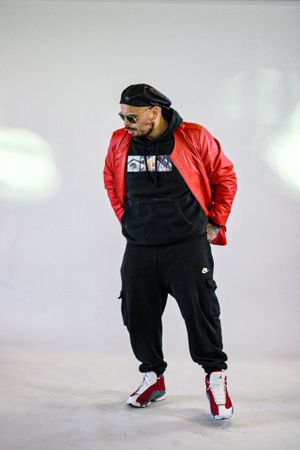 Figure in oversized black outfit and red jacket strikes dynamic poses in studio setting.
