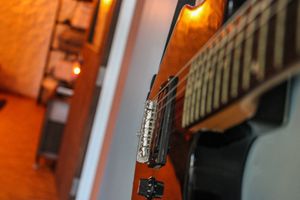 Close-up detail of electric guitar bridge and pickup with warm lighting.