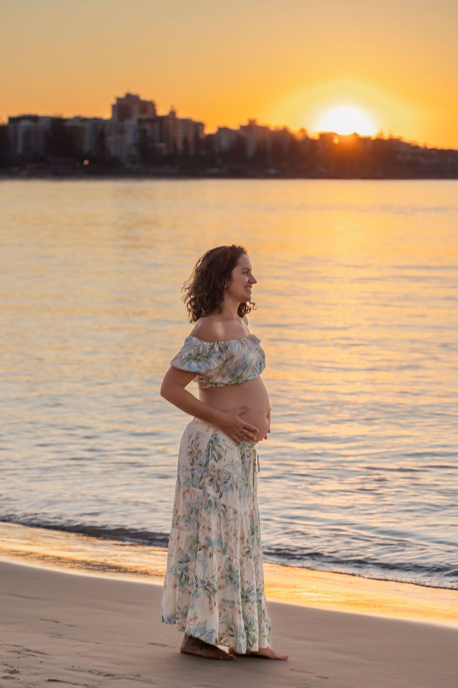 A floral dress silhouette against a golden beach sunset creates a dreamy coastal scene.
