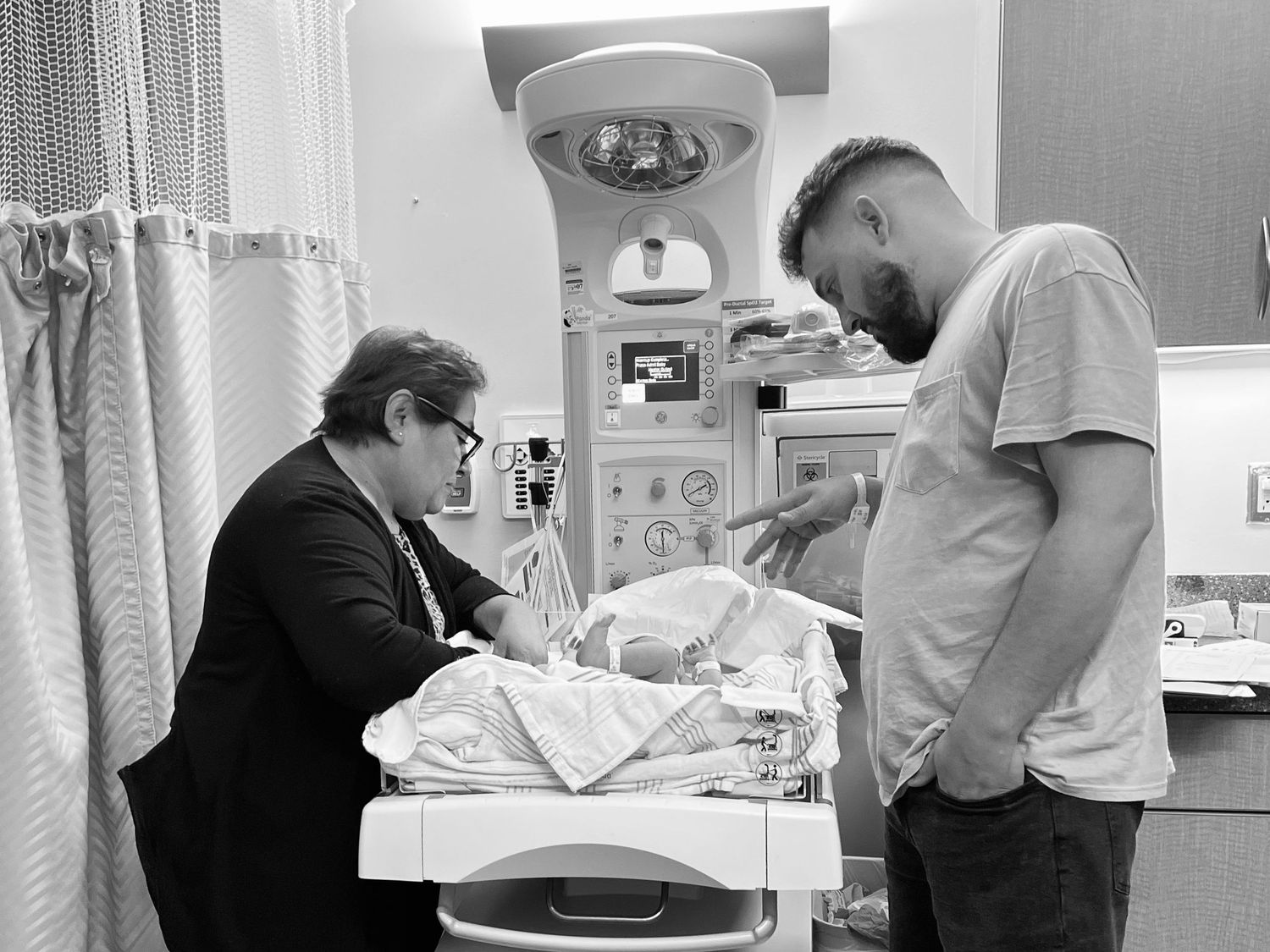 Medical staff examining a newborn baby under hospital lighting equipment.