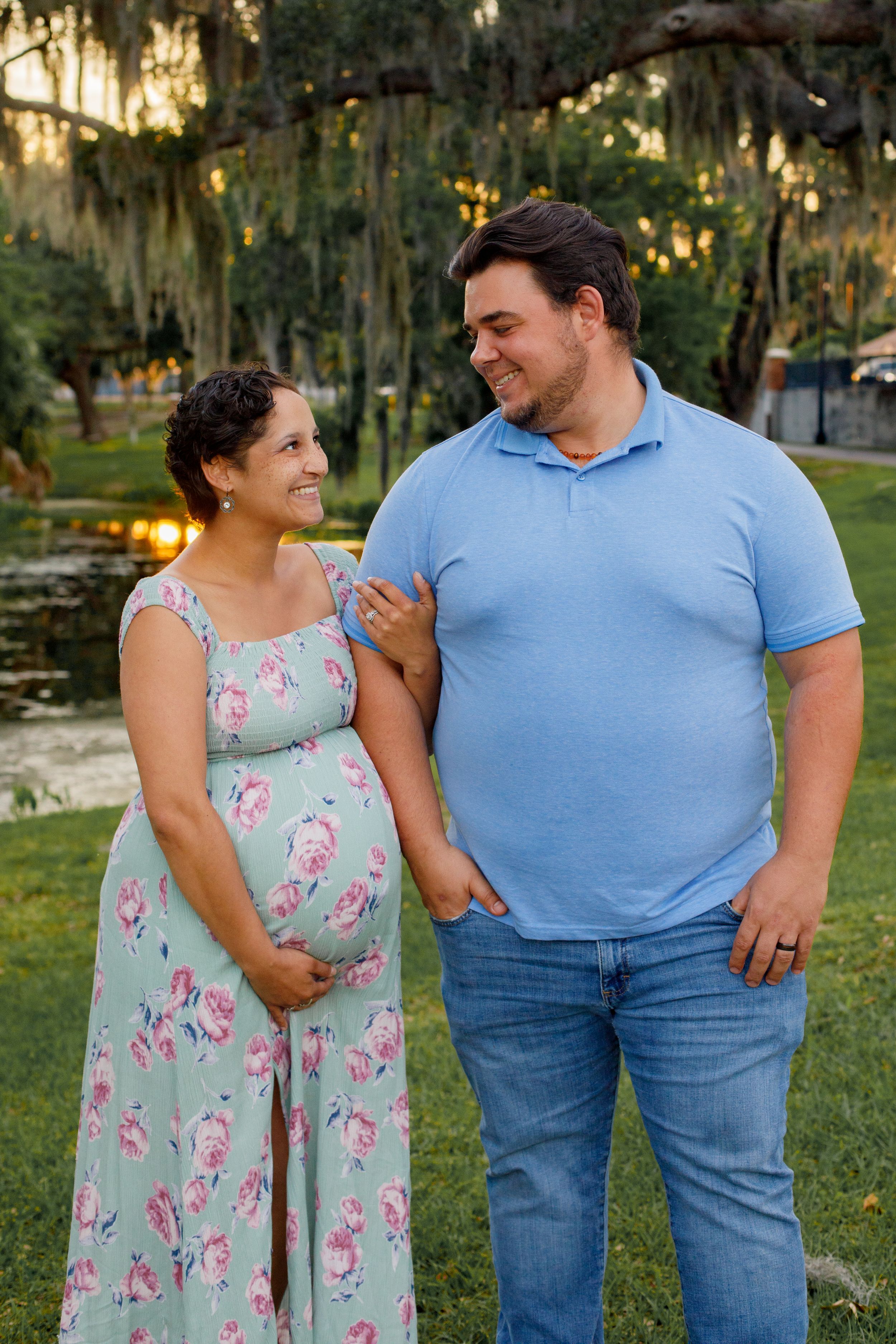 A couple shares a romantic moment in a garden setting wearing coordinating blue and floral outfits.