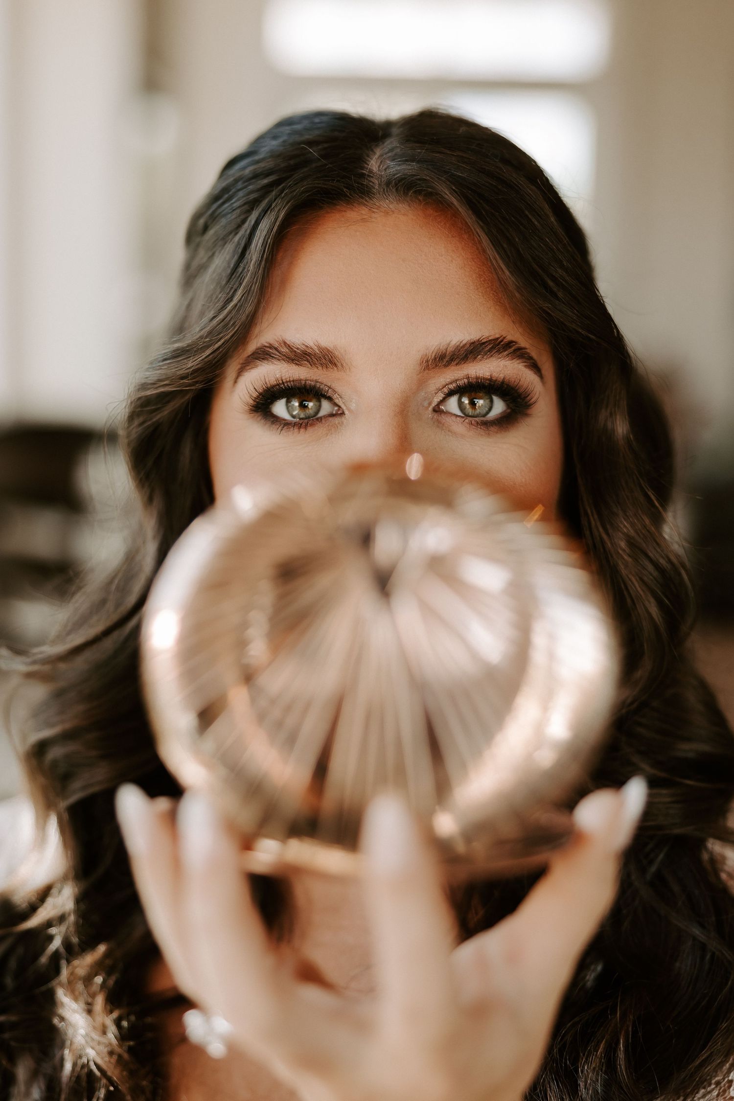 Close up portrait through crystal ball creating unique refraction effect with dark wavy hair and dramatic lighting.