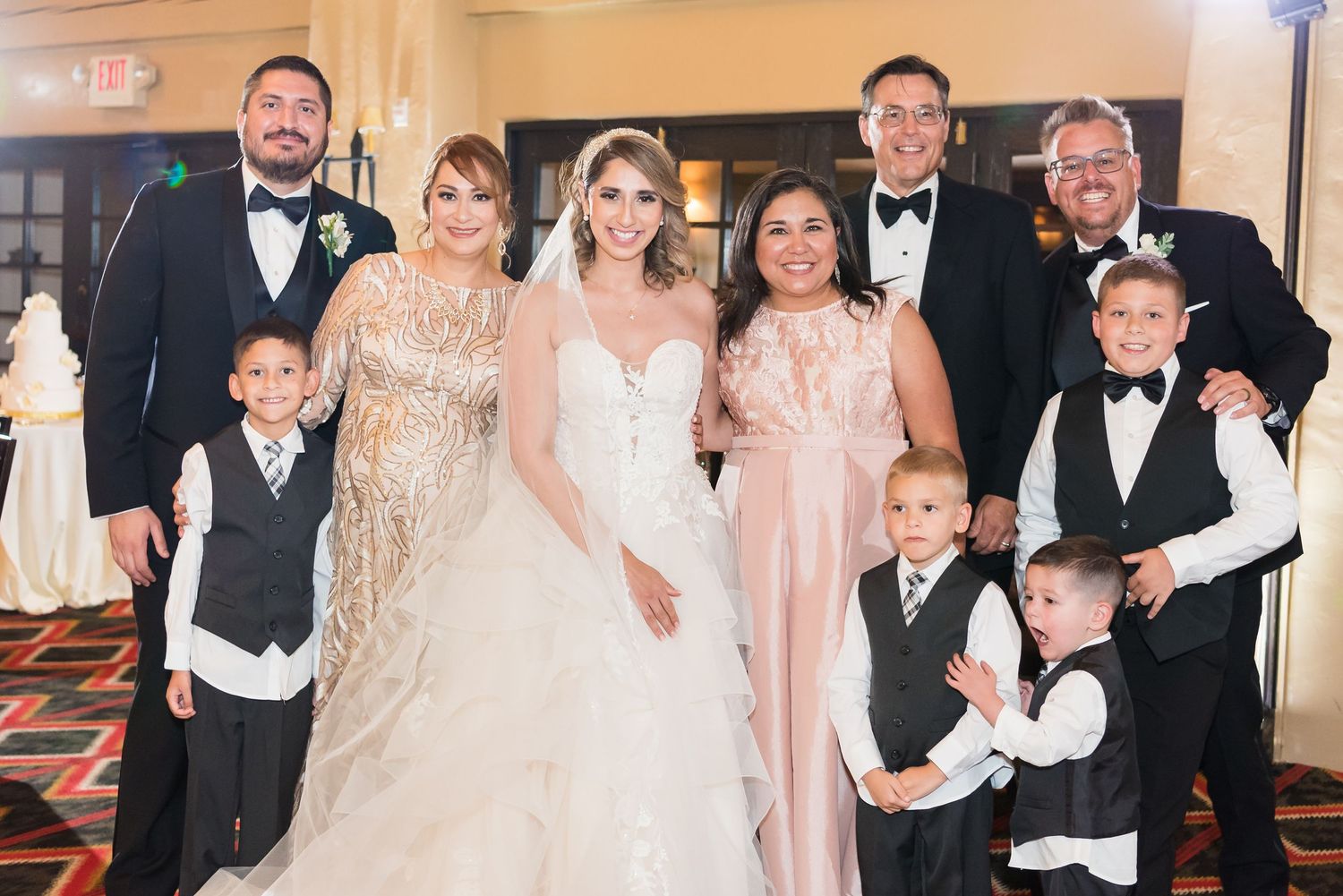 Wedding party in formal attire including groomsmen in tuxedos and bridesmaids in blush dresses.