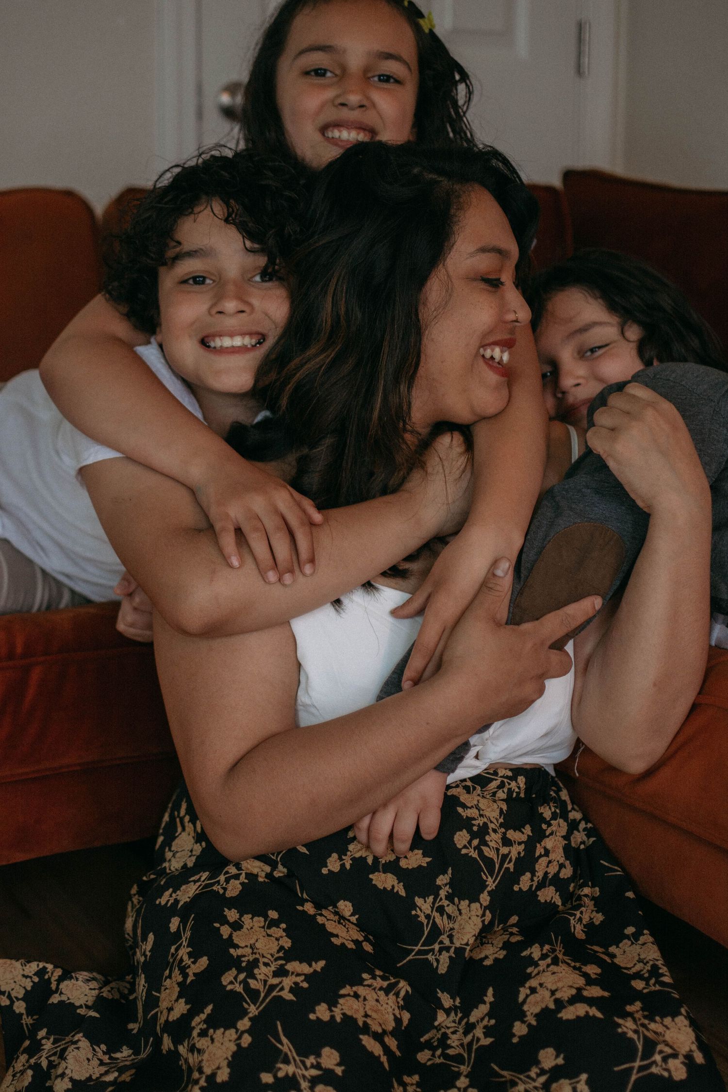 a mother being hugged by her 3 smiling children